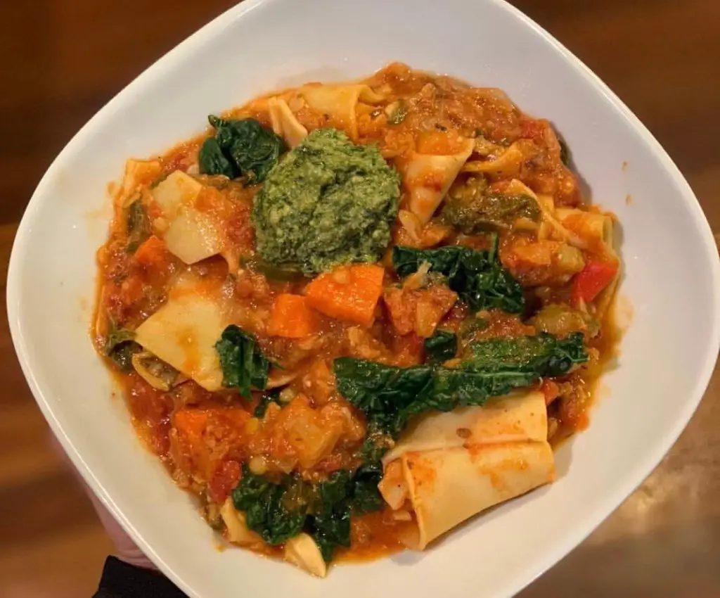 Lasagna soup topped with pesto in white bowl.