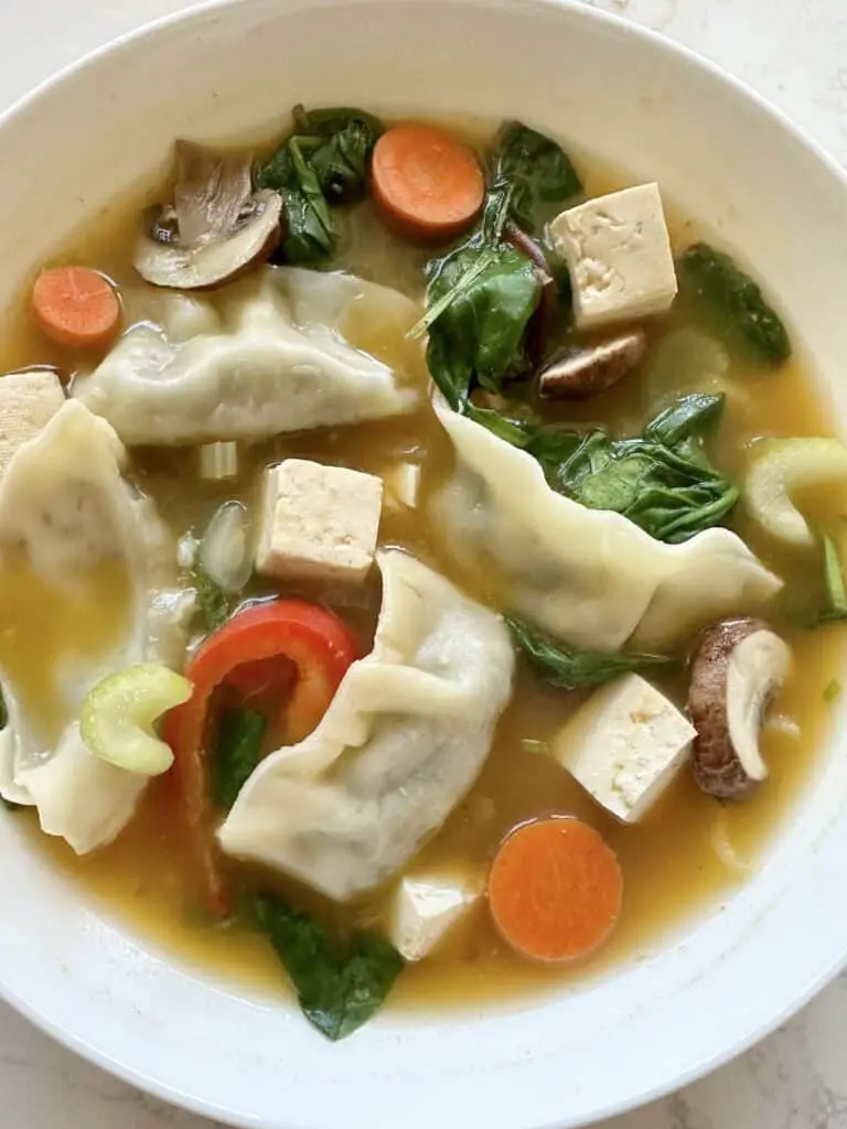 Bright and beautiful white bowl of Easy Veggie Gyoza Soup!