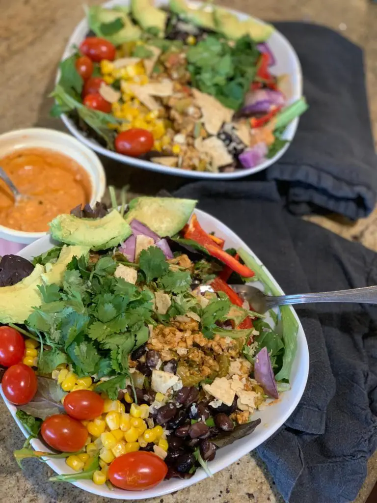 Vegan taco salad bowls with smaller dressing bowl in the middle.
