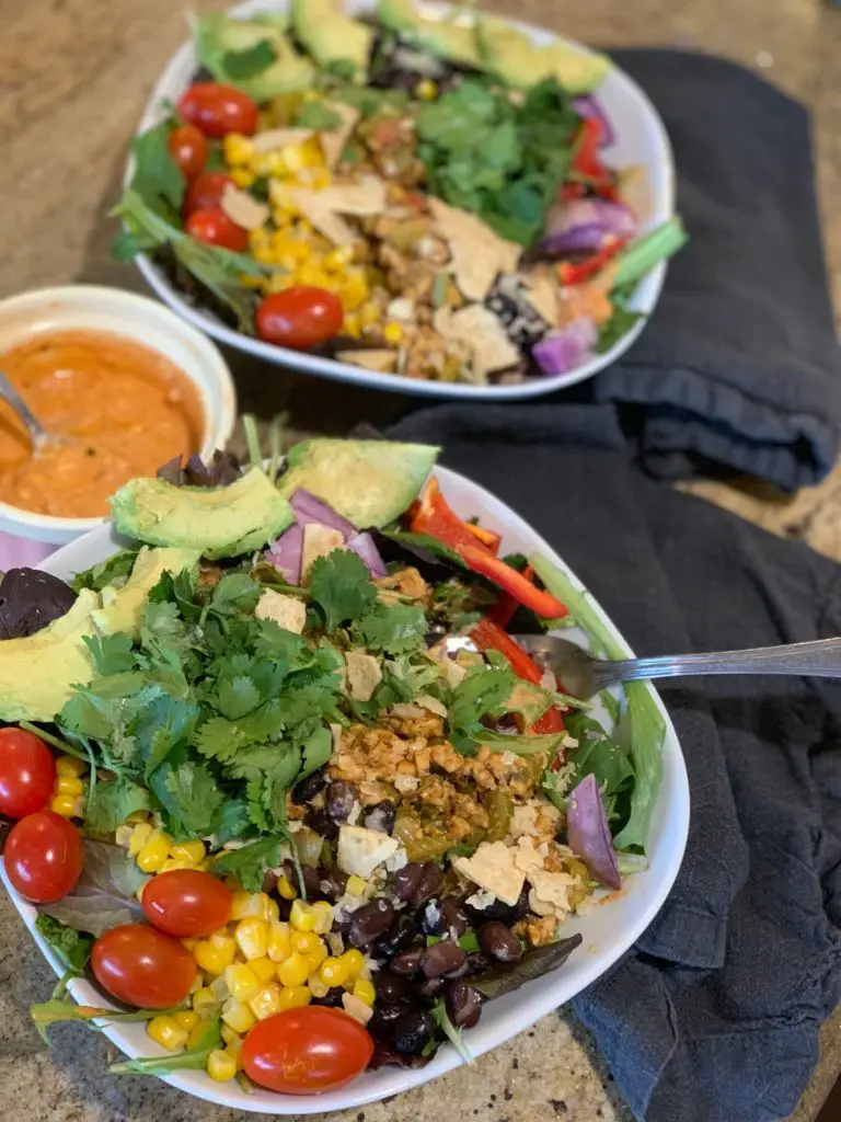 Messy taco salad bowl with fresh herbs and salsa/yogurt dressing.