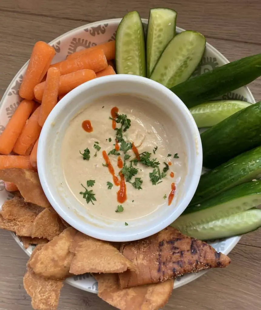 Plate of veggies with a bowl spicy tahini sauce in the middle for dipping.