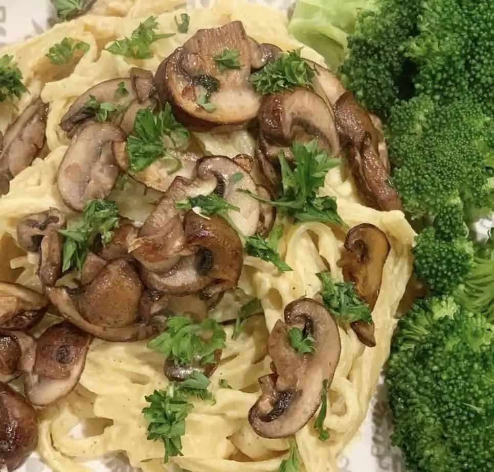 Vegan alfredo topped with sauteed mushrooms and parsley.