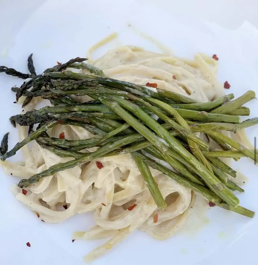 Vegan alfredo topped with roasted asparagus and red pepper flakes.