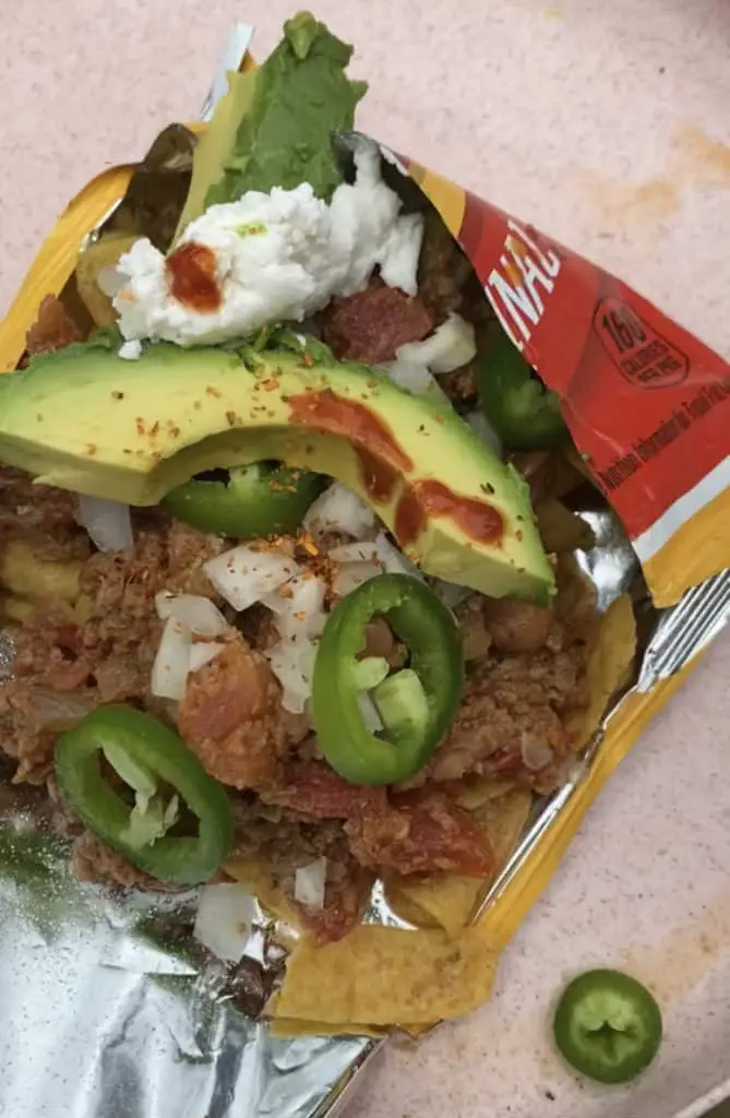 Frito Pie: ripped bag of fritos on the bottom, with frito chips, then Killer Vegan Chili, then onions, jalapenos, avocado, vegan sour cream, and hot sauce toppings.