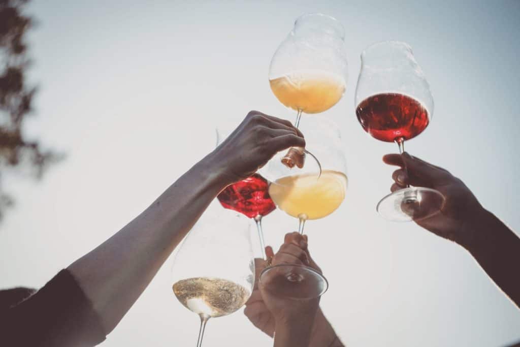 Showing wine clarity with a toast, camera angle up towards the sky to see through the white and red classes.