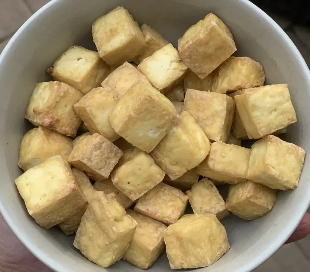 Bowl of air fried tofu as 1 inch cubed nuggets.