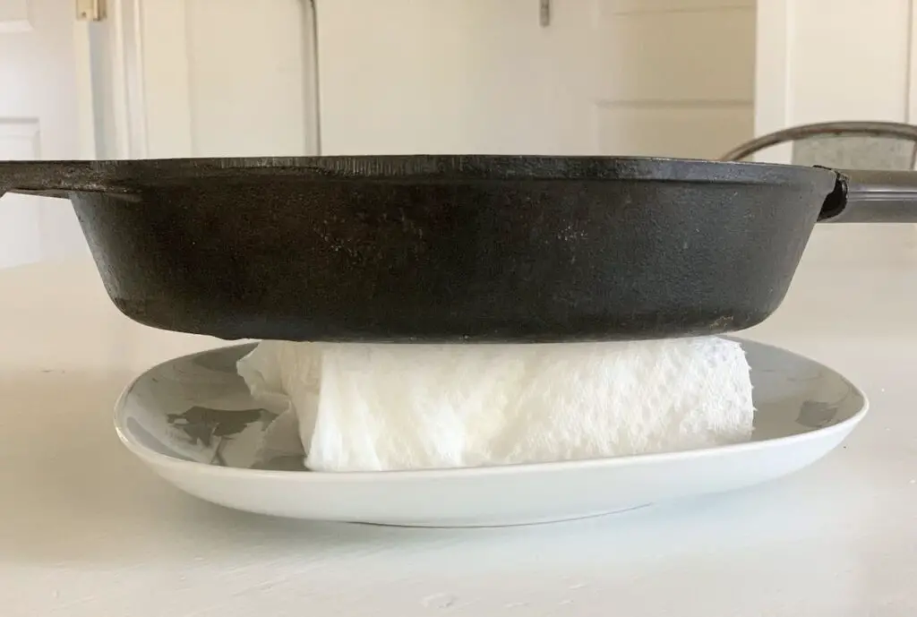 Wrapped tofu on plate with heavy pot on top of it to press the water out.