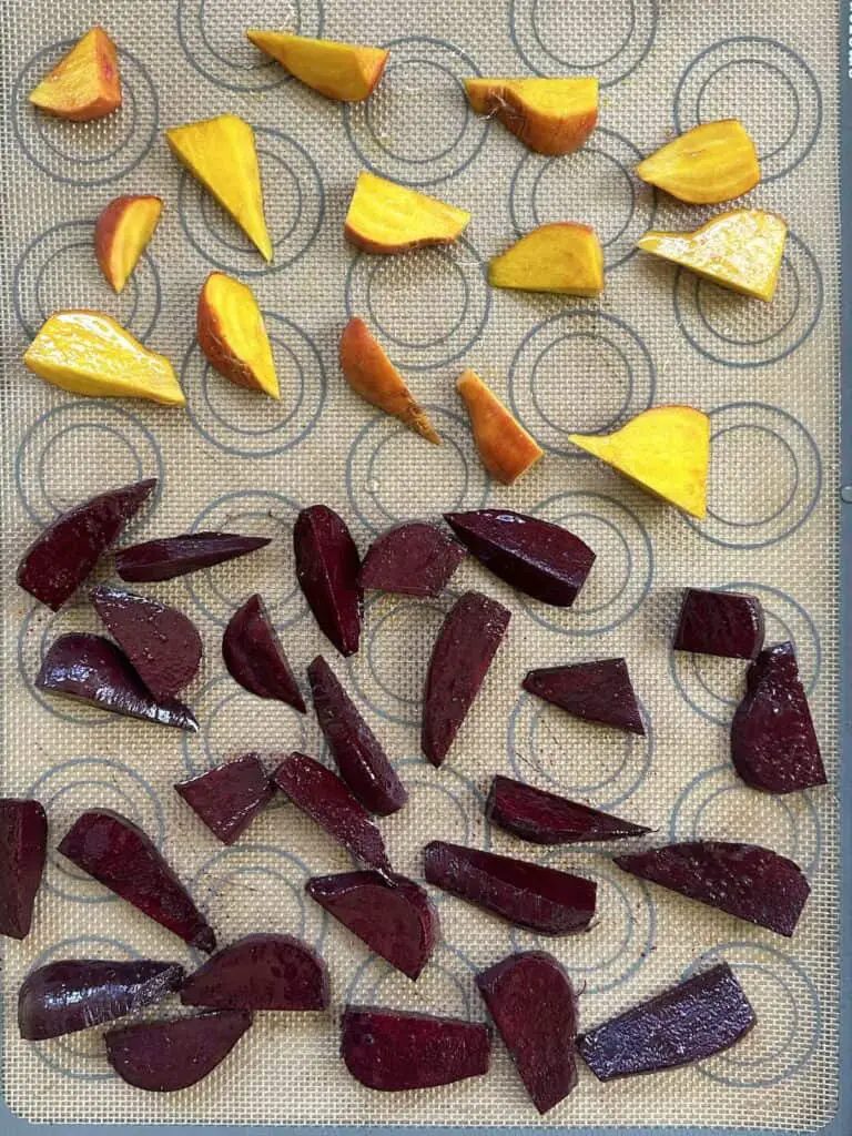 Golden and red beets on baking sheet and silicon liner ready for oven.