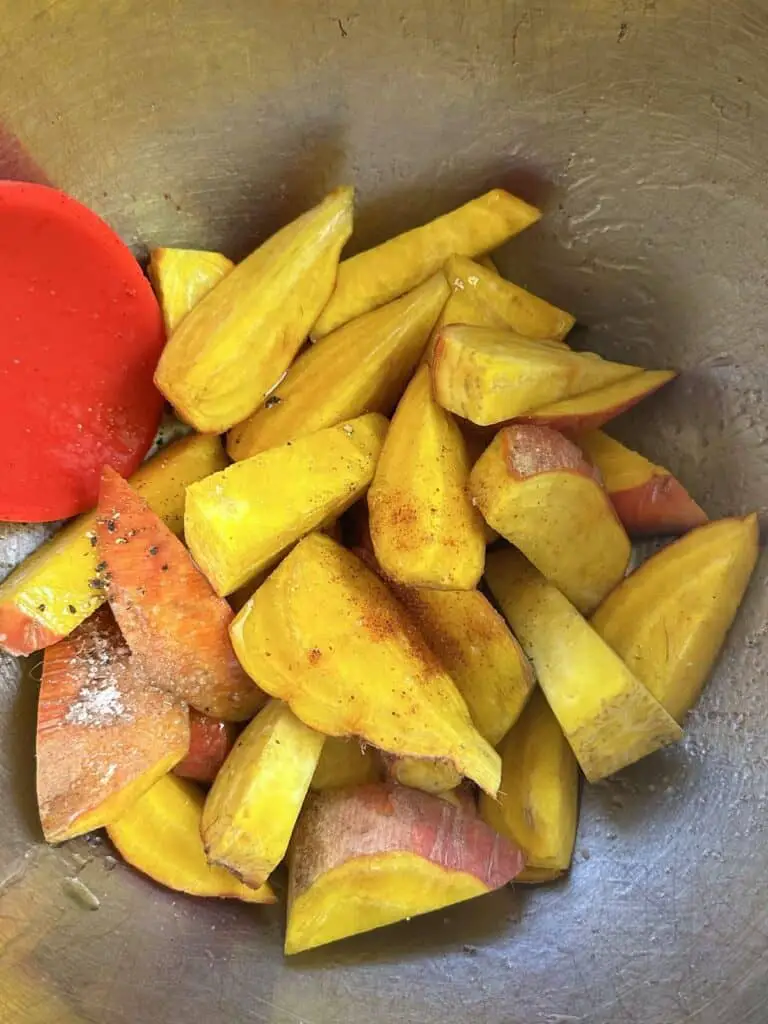 Mixing golden beets, oil, salt, and pepper in bowl.