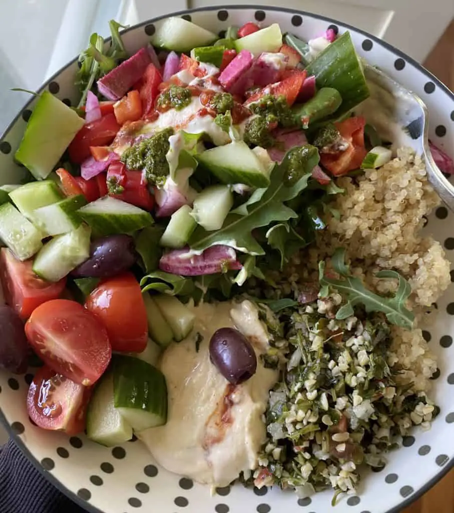 Greek inspired salad with tabbouli in white bowl with black polkadots.
