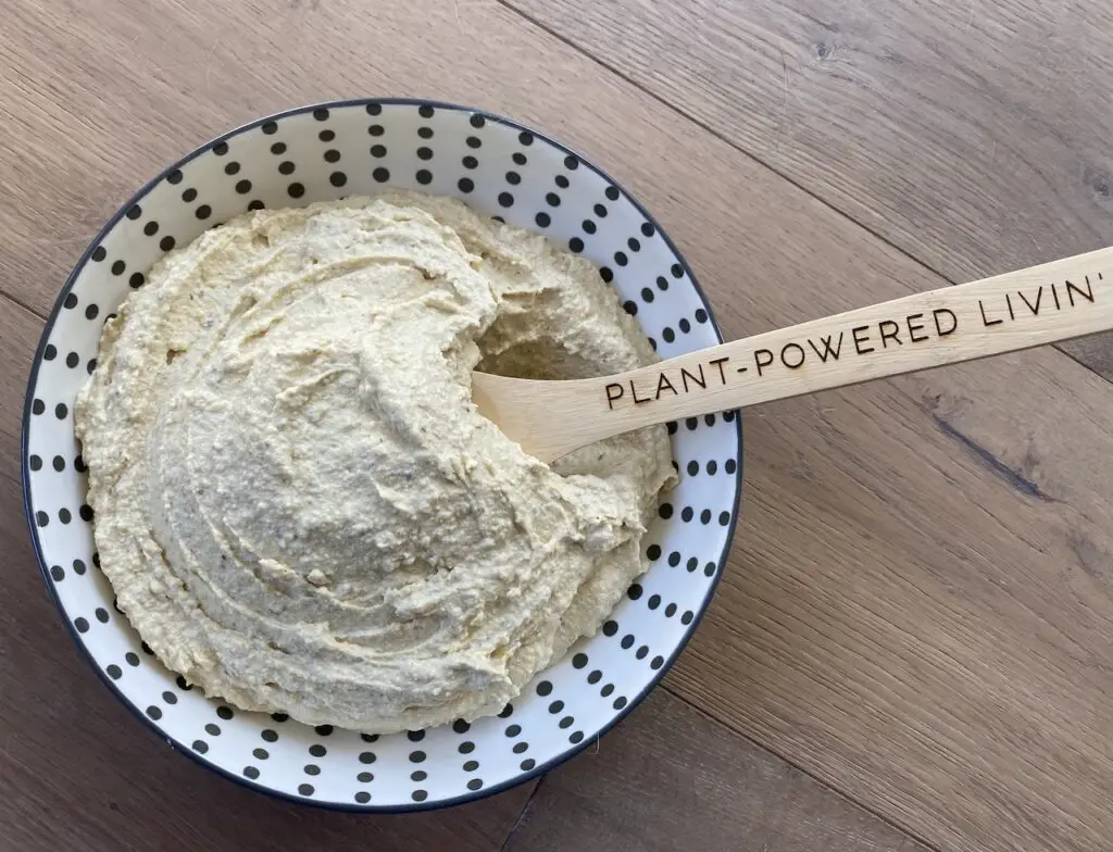 Bowl of easy vegan ricotta cheese with "Plant-Powered Livin" spatula dipped in.