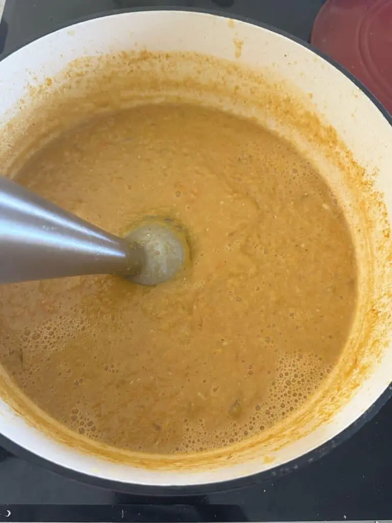 Using immersion blender to puree soup.