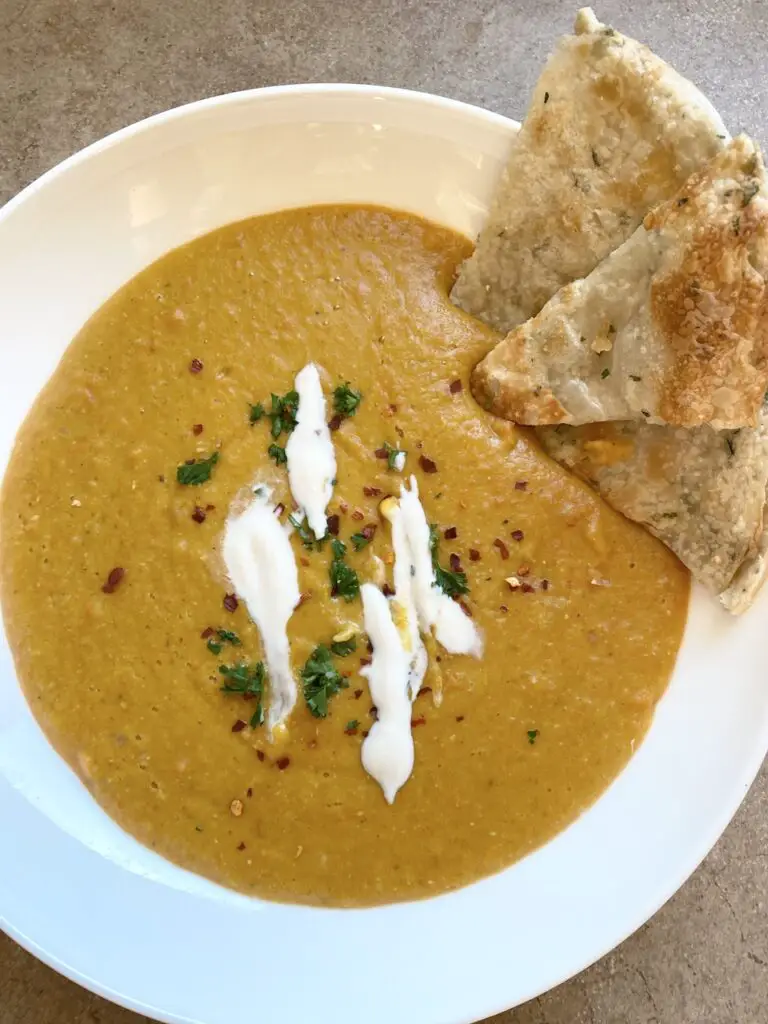 Carrot and Lentil Soup topped with vegan yogurt and fresh herbs.