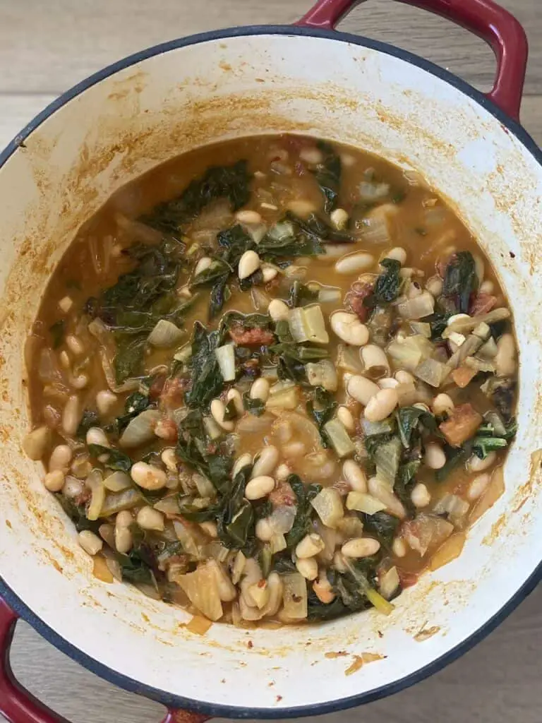 Gorgeous pot of vegan white beans and greens with tomatoes and fennel.