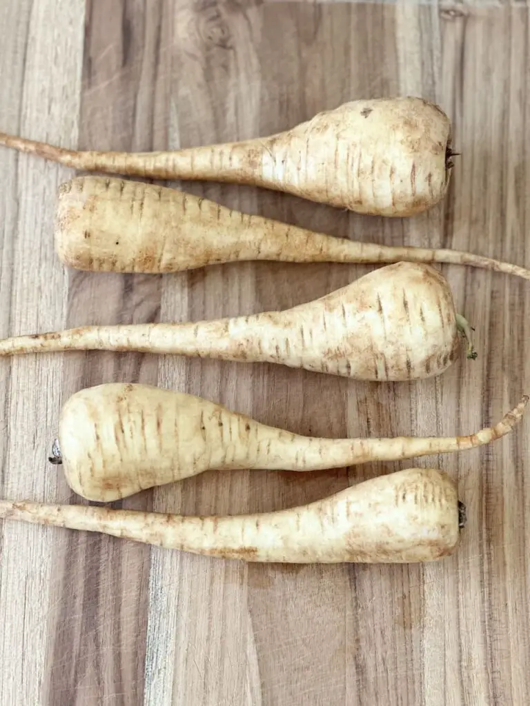 Whole parsnips on a cutting board.