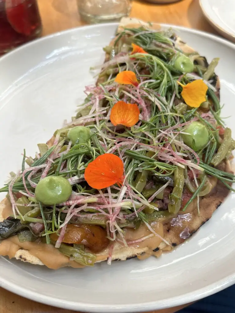 Gorgeous vegan tlayuda, or large tostada, with edible flowers and avocado crema at Maximo.