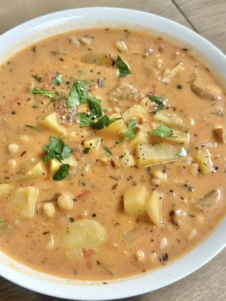 Close up of potato chickpea chowder in round white bowl.