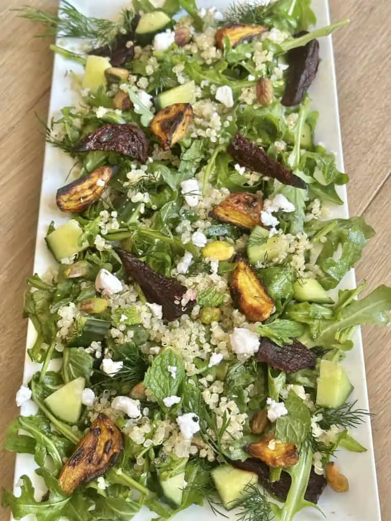 Roasted beet and cucumber salad with fresh herbs and quinoa, shown on a long rectangular plate.