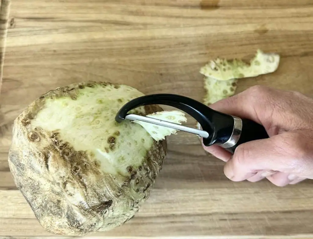 Peeling celery root on cutting board.