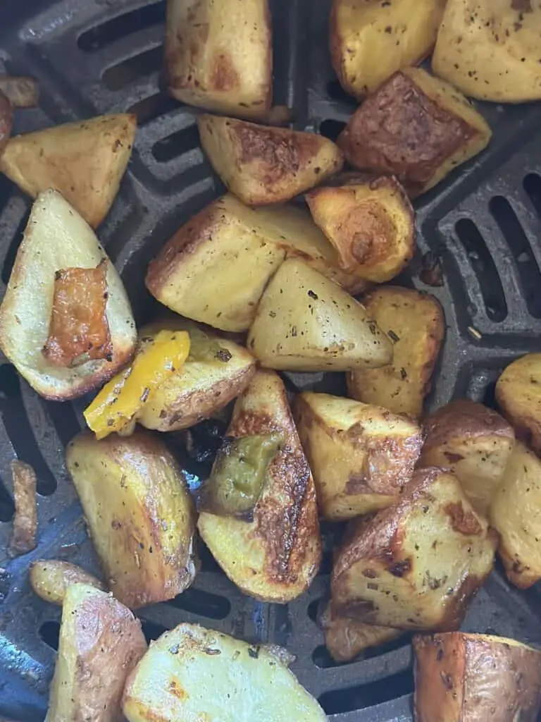 Air fried roasted potatoes in the air fryer basket.