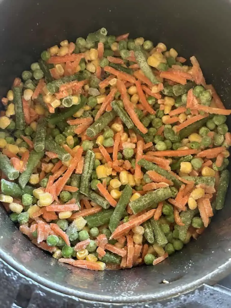 Frozen vegetables in air fryer basket.