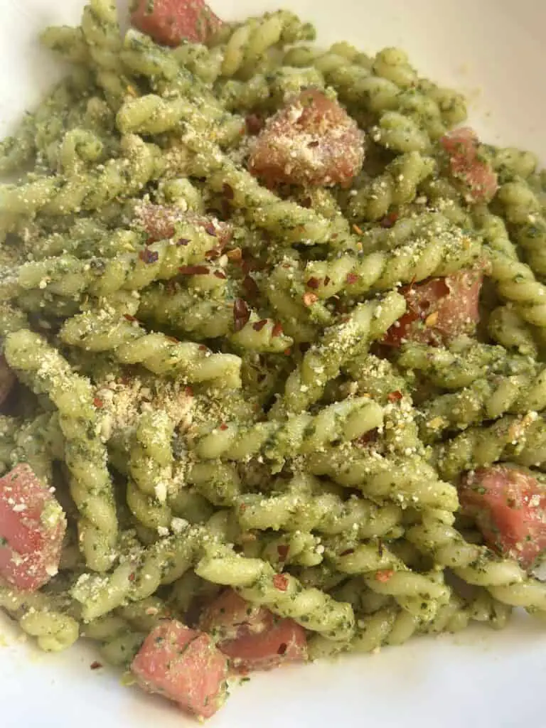 Bowl of vegan pesto and tomato pasta.
