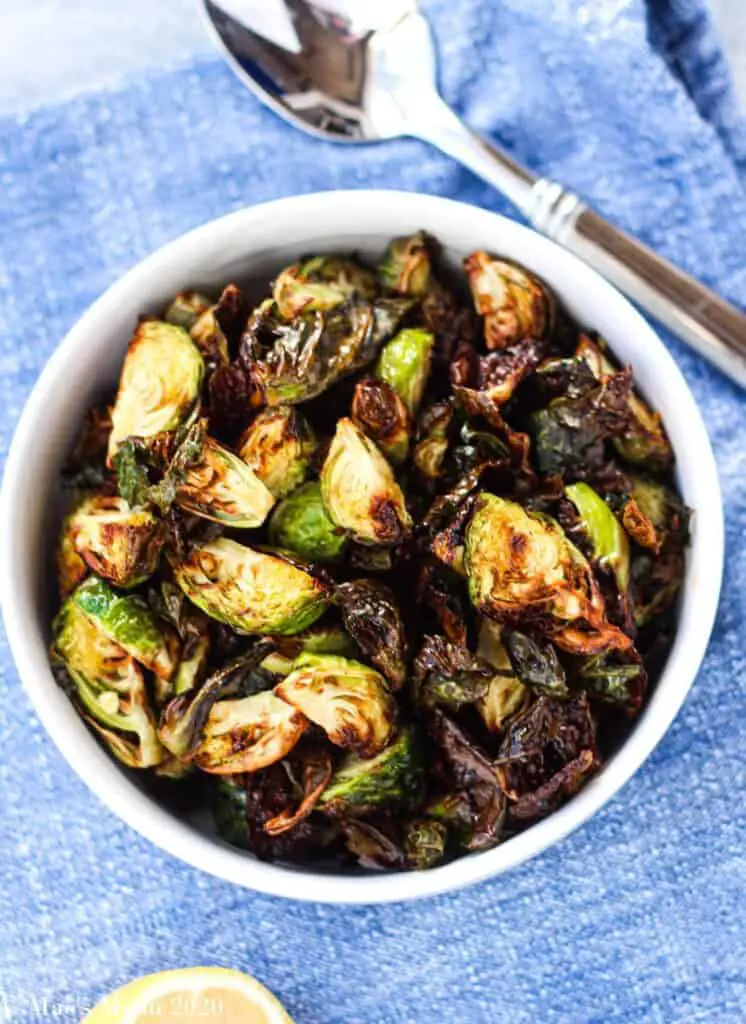 Brussels sprouts in a bowl with a spoon on the side.