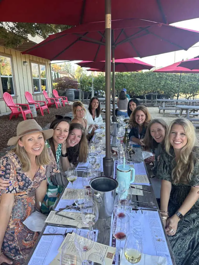 Nine gorgeous ladies enjoying food and wine pairing at an outdoor picnic table at Mayo Family Reserve.