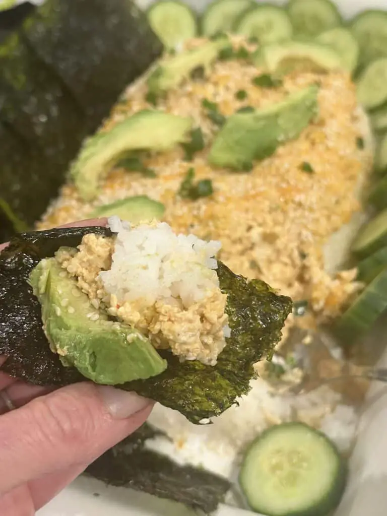 Making a bite: take nori sheet and fill with avocado, tofu mixture, and rice for the most delicious bite!