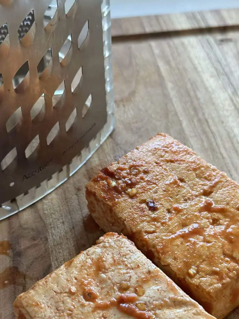 Tofu and grater on cutting board.