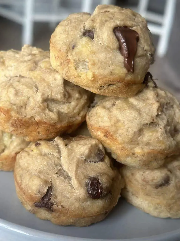 Close up of 3-ingredient banana oat muffins stacked on a plate, some with chocolate chips in them.