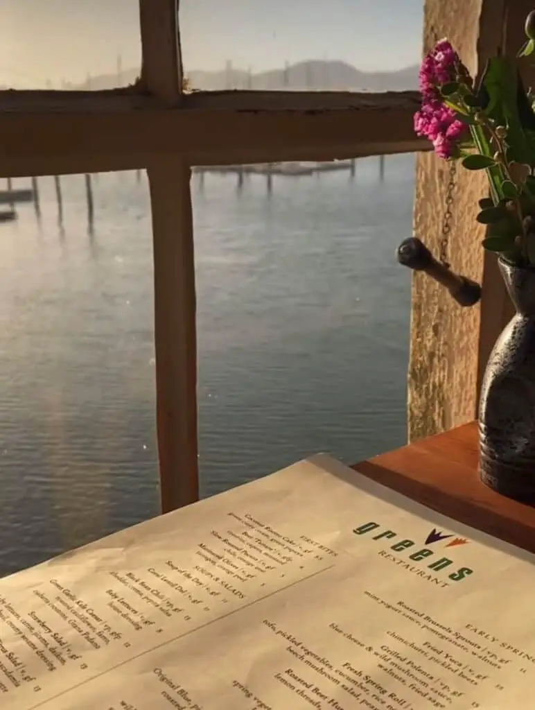 Gorgeous scenery  on the Bay at a window table with pink flowers and menu at iconic vegetarian restaurant, Greens.